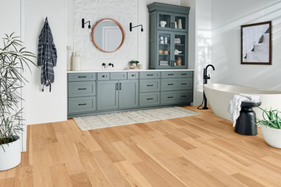 warm toned hardwood flooring in bathroom with bathtub and vanity.